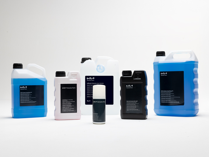 Eine Hand gießt Motoröl aus einer Flasche in einen Trichter über einem offenen Motorraum.